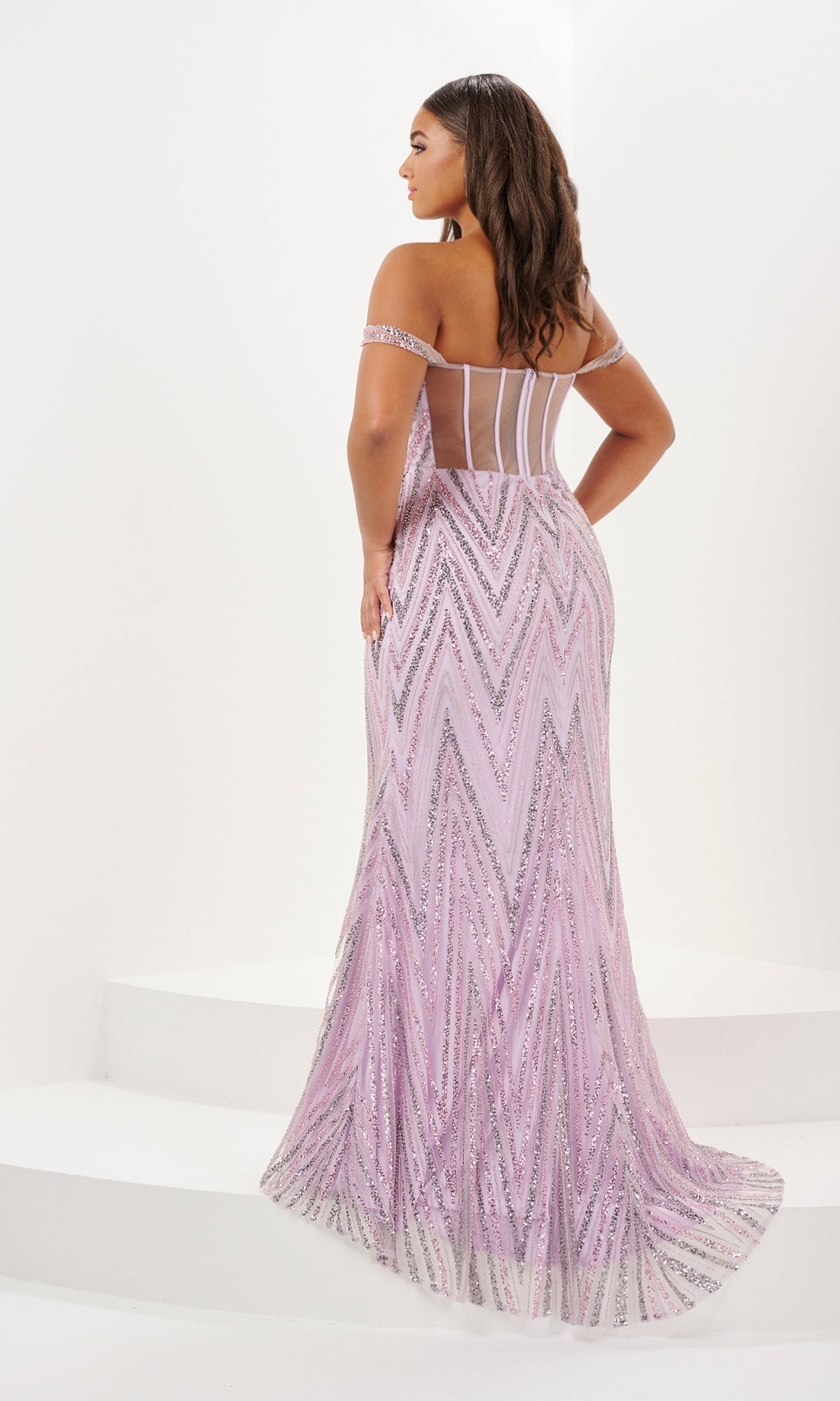 A woman stands on white steps wearing the Tiffany Long Plus-Size Sequin Prom Dress 16120, a floor-length, off-shoulder lavender gown with chevron patterns and a sheer back panel.